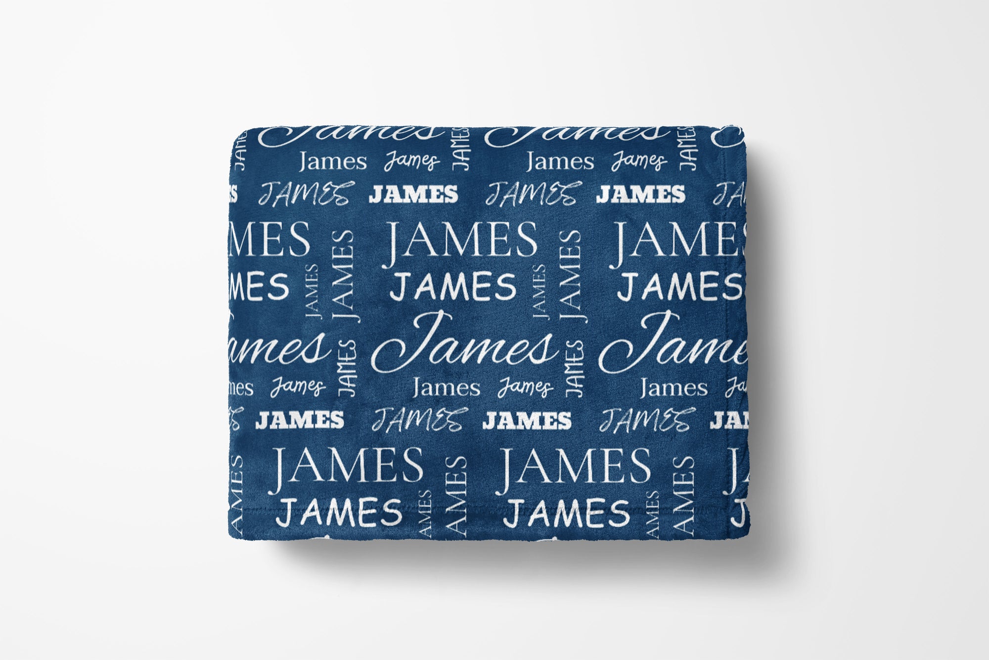 Folded blue blanket with 'JAMES' text pattern on a white background